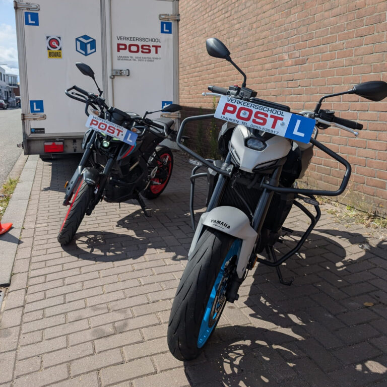 Twee lesmotorfietsen van Verkeersschool Post IJmuiden geparkeerd voor een instructievoertuig
