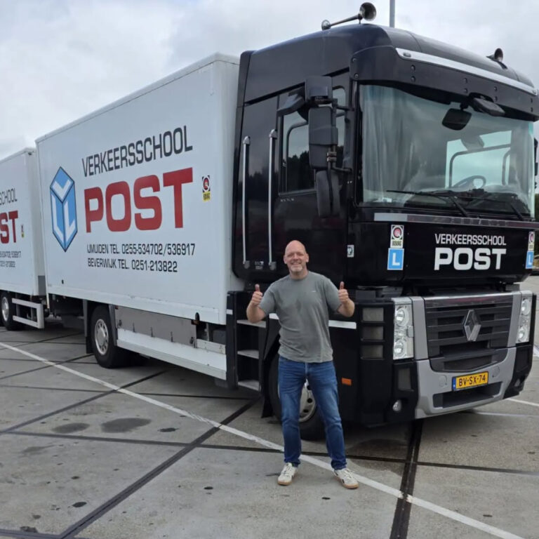 Blijde geslaagde kandidaat met duimen omhoog voor de lesvrachtwagen van Verkeersschool Post in IJmuiden